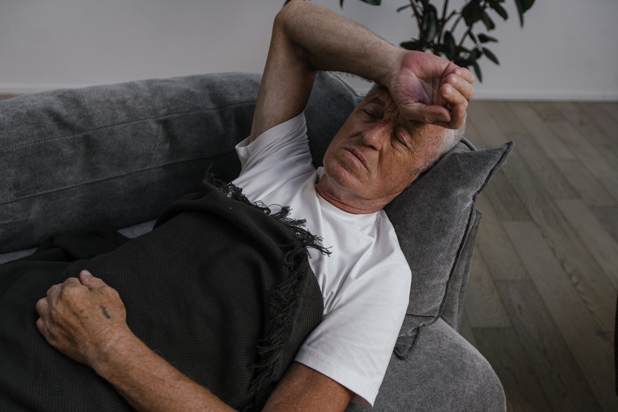 Senior liegt mit Schwindelanfall auf dem Sofa